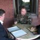 Military officer discussing documents with two men at a round table.